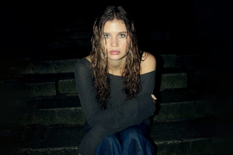 Artisten Ida-Lova sitter i grå tröja och blå jeans.