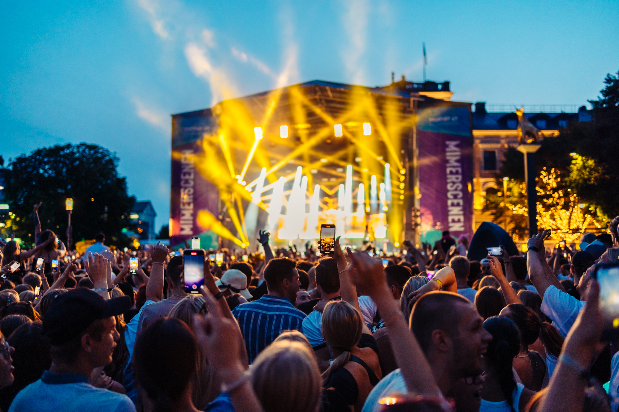 Publikhav framför en uppkyst scen under kvällstid.