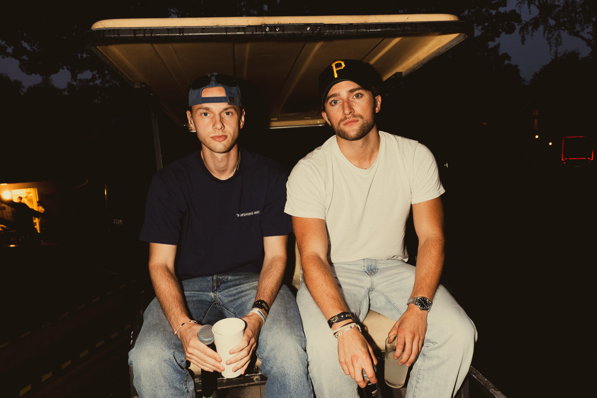 Musikgruppen Soppgirobygget sittande bak på en golfbil, iklädda t-shirtar och jeans.